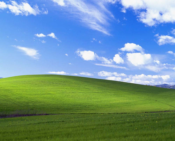 Image showing vibrant green hills and blue sky with clouds - image used by operating system Windows until 2016