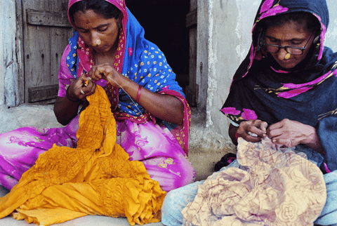 Women practising the art of tying knots manually to create intricate bandhani patterns.
