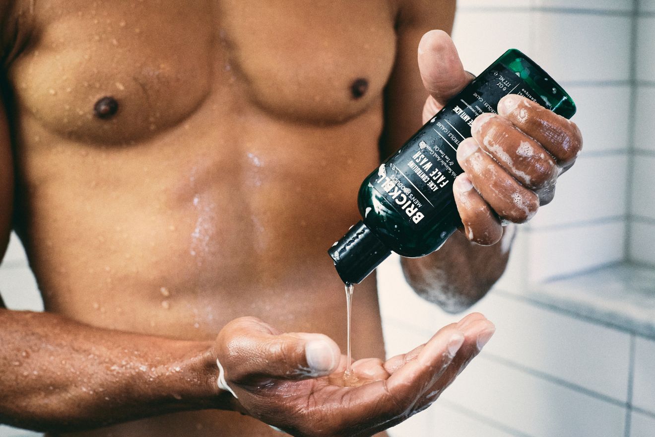 Man squeezing face wash from bottle into hand