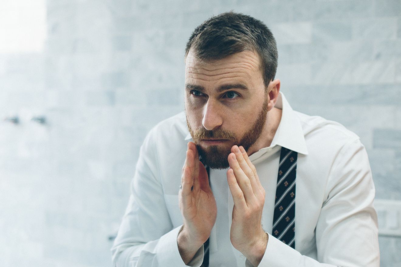 Bearded man lookin in mirror