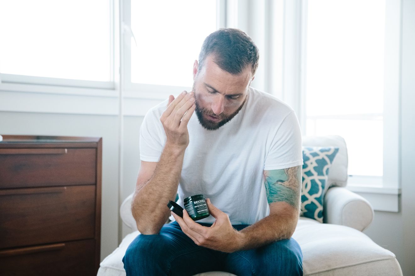 Man with tattoo applying skincare product