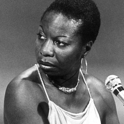 Nina Simone singing and wearing large hoop earrings.