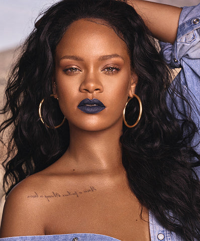 Rihanna is wearing dark lipstick and large hoop earrings