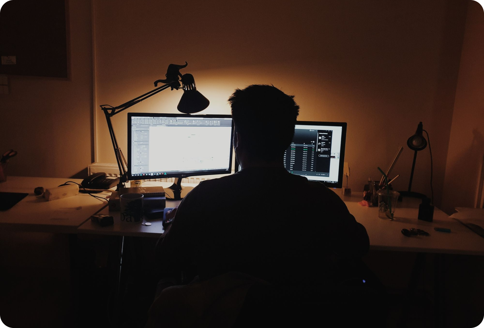 Man sitting in front of two computer screens at a desk