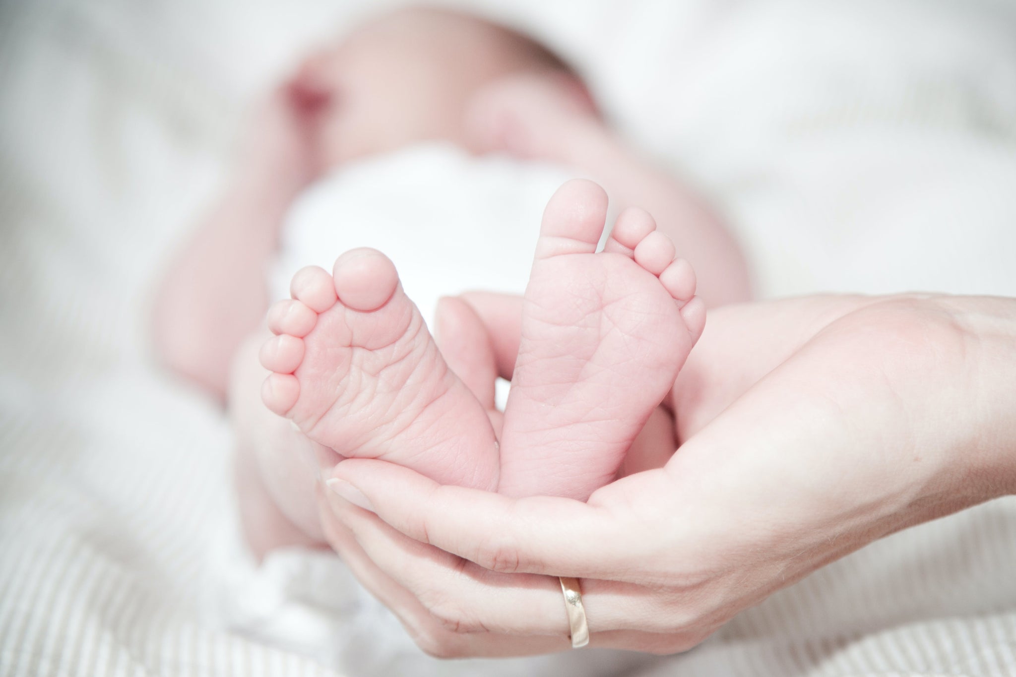 Foreground shows infant feet held by parent's hand.