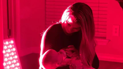an image of a woman carrying a baby receiving red light treatment.