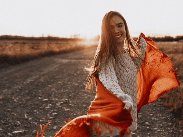 an image of a happy woman strolling along a gravel road.