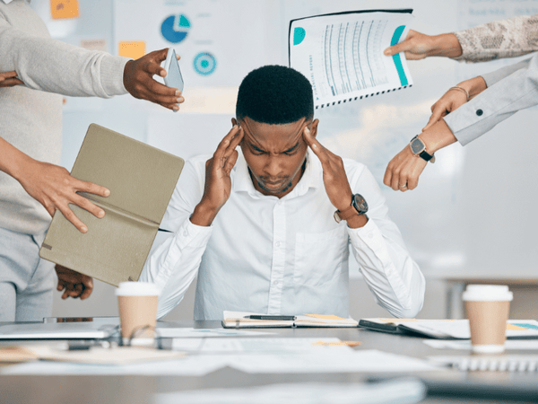 an image of a man bombarded with tasks in the office, suffering form Anxiety.