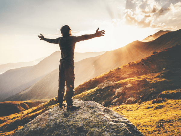 an image of a man taking in sunlight with open arms