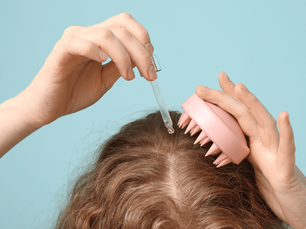 an image of a woman applying tincture oil on her scalp