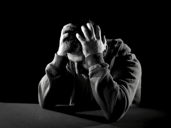 an image of a man holding his head, experiencing depression.