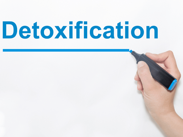 an image of a person writing the word detoxification