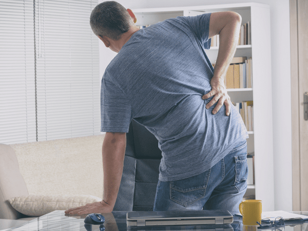 an image of a man holding his back in pain.