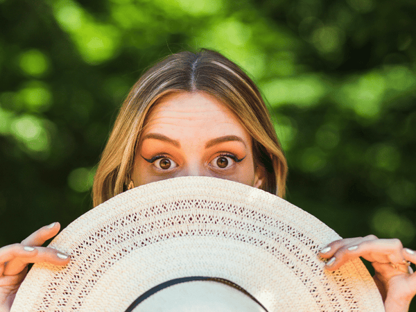 an image of a woman hiding from the sun using a hat.