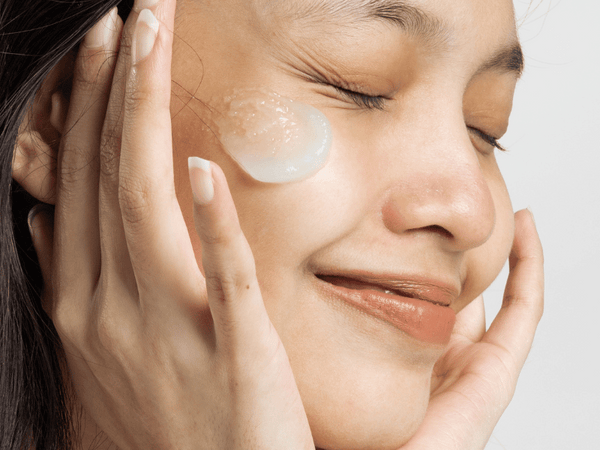 an image of a woman applying topical cream on her face.