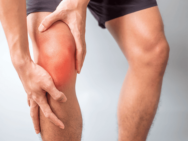 an image of a man holding his knee due to patellar tendinitis