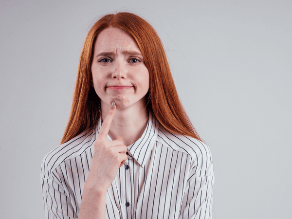 redhead student woman squeezing her pimples, removing pimple from her face white background studio