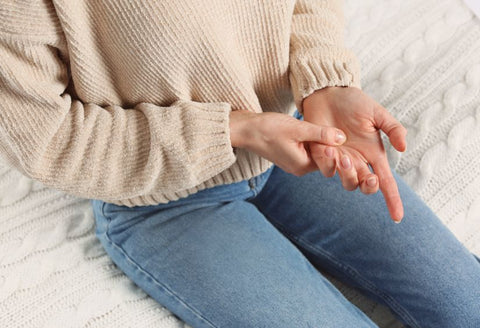 Best trigger finger clothing: close up of a woman's hands as she rubs one, signaling pain