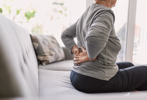 chronic pain bra: woman with back pain sitting down