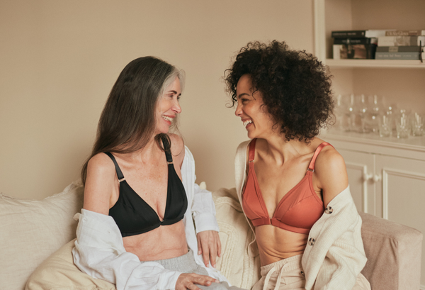 Two smiling friends sitting on the couch in their Springrose velcro front closure bra