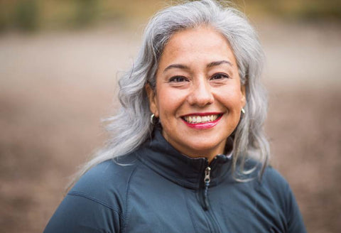 Who can an adaptive bra help: beautiful middle aged woman with silver hair, smiling widely at the camera