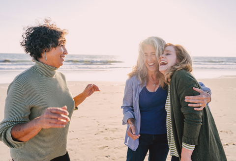 Adaptive bras for seniors: a group of attractive older women hugging and laughing on the beach