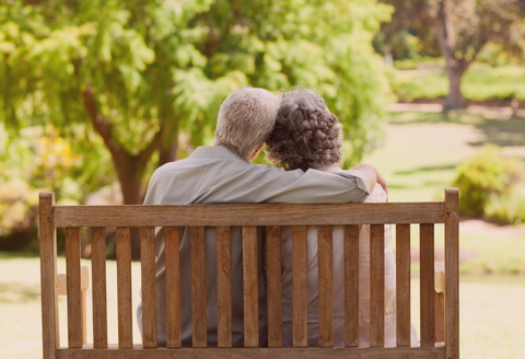 Older couple lovingly cuddling on a park bench