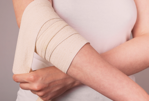 Recovery from tennis elbow surgery: a woman wrapping her elbow and arm with a bandage