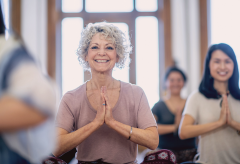 Osteoarthritis tips - Mature women in a yoga class, smiling gently