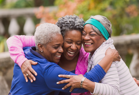 Bra for fibromyalgia: three mature friends hugging while wearing colorful clothing