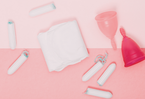 ehlers danlos syndrome and periods: a collection of period products displayed on a pink background