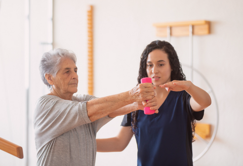 tips for living with a broken arm: a woman does physical therapy on her arm with the help of a caregiver