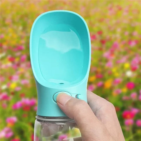 Human hand holding a Turquoise Travel Water Bottle and pressing the water dispenser button