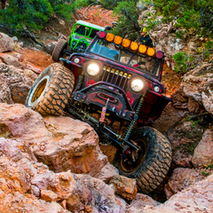 A jeep crawling itself out of rocky terrain