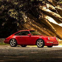 A Porsche 911 SC in front of a scenic landscape