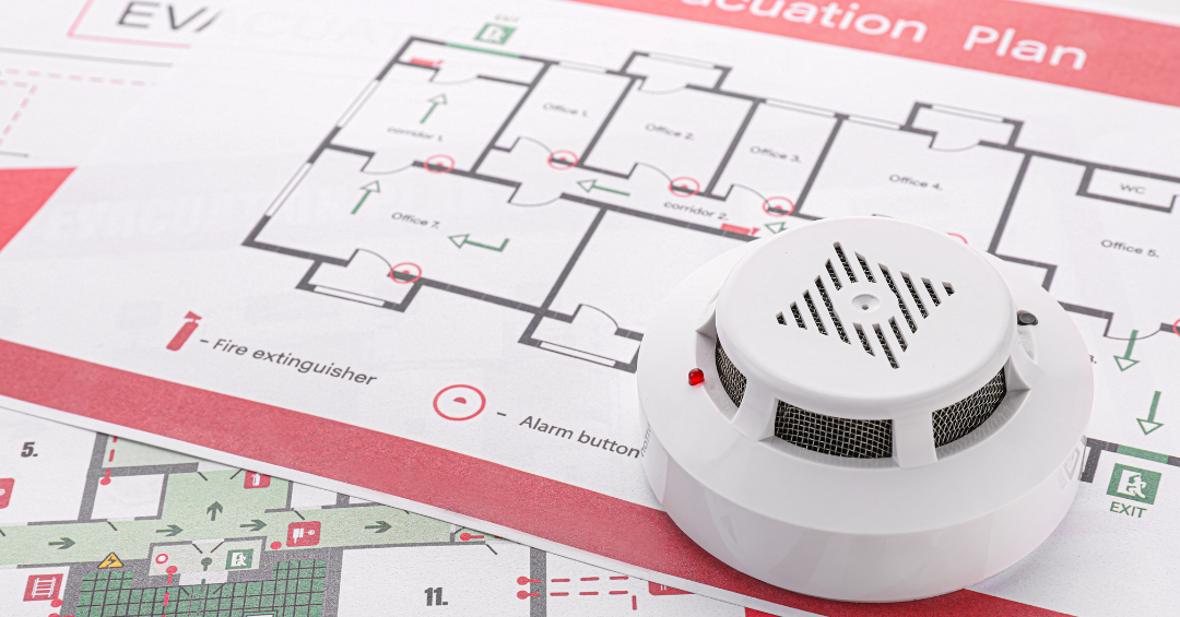 smoke detector sits on top of a fire escape plan that shows the location of the firefighting equipment and safe exit points