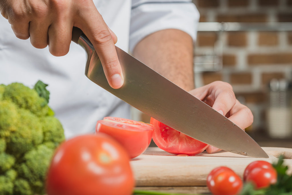 Man chopping tomato with sharp kitchen knife