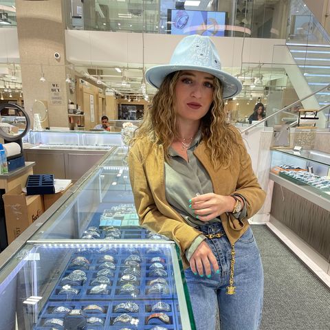 Julia Azeroual, a social media influencer, posing for a photo and leaning on a glass display of watches