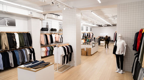 a large open clothing store filled with different clothing items with a wooden floor