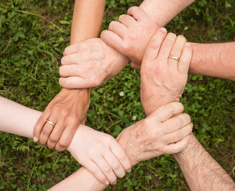 Diverse group of hands holding wrists in a circle, symbolizing unity, support, and collaboration