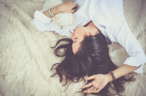 Image of a women on her back asleep with her arm above her head