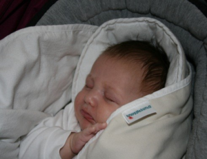 Snugglebundl - Importance of Supporting a Baby’s Head Blog - Image of a baby asleep wrapped in the Snugglebundl