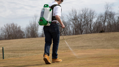 man spraying golf course with battery powered sprayer