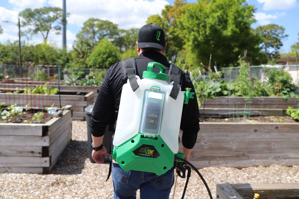 man with backpack battery sprayer in community garden