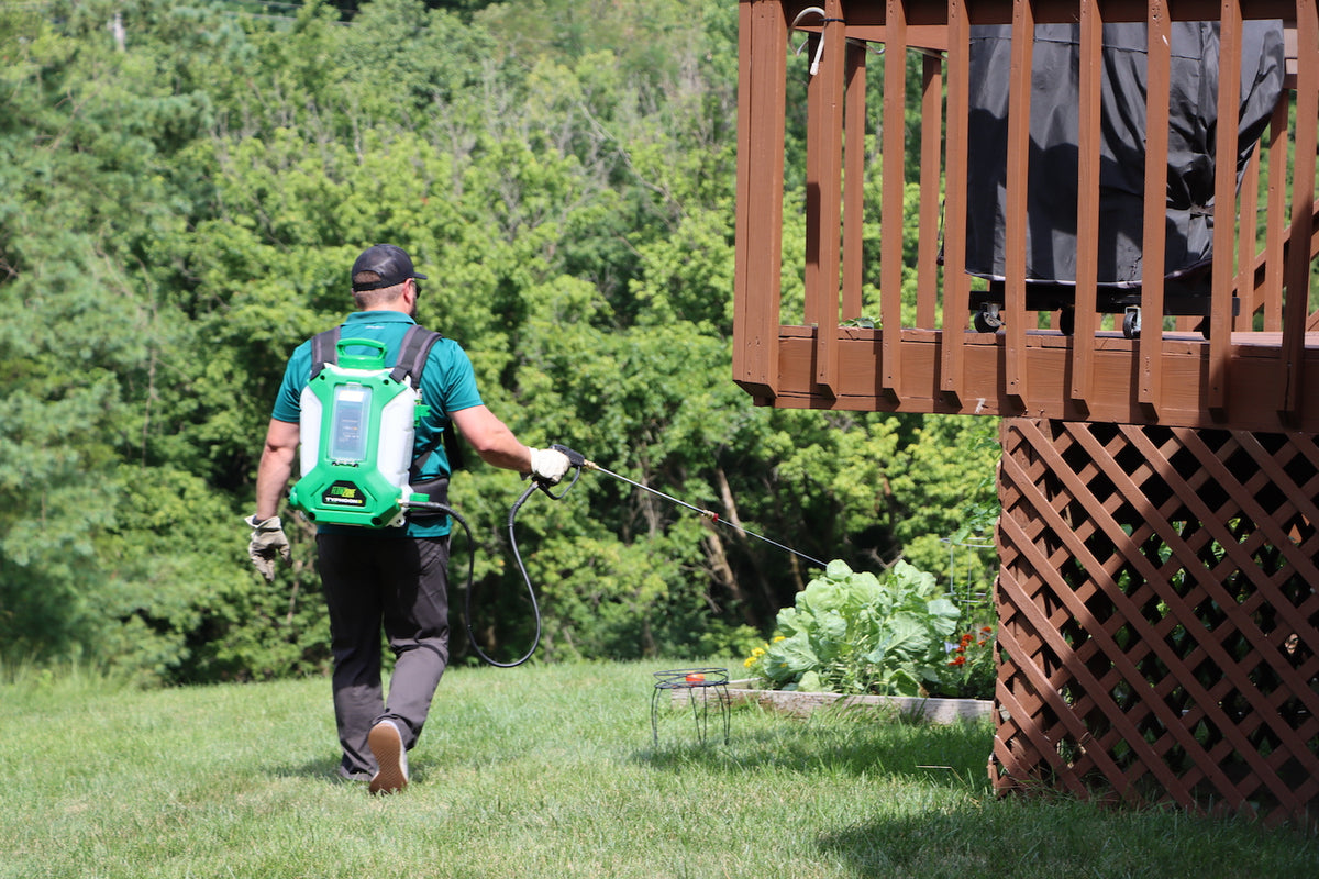 man spraying around deck with backpack sprayer