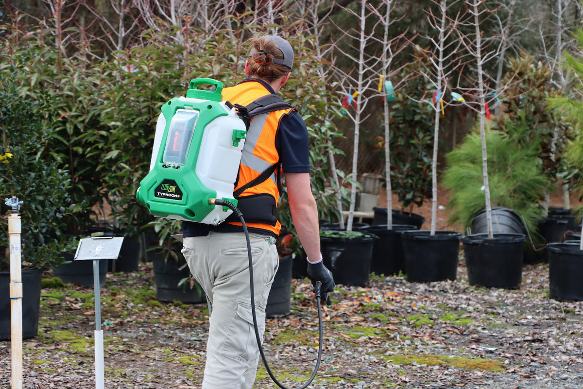 man with battery backpack sprayer in a plant nursery