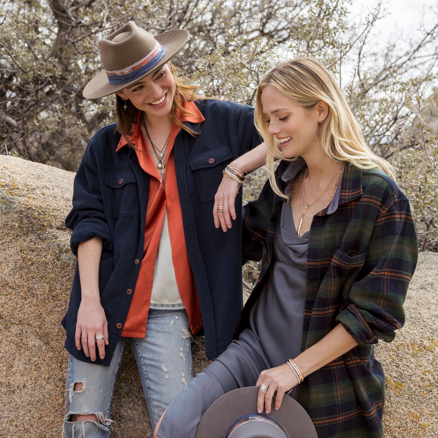 Two friends enjoying talking outdoors wearing camel designer hat, grey designer hat, black gold and rose gold diamond jewelry, and silk apparel over jeans in casual luxe personified; phone 323-404-2959 for shopping help.