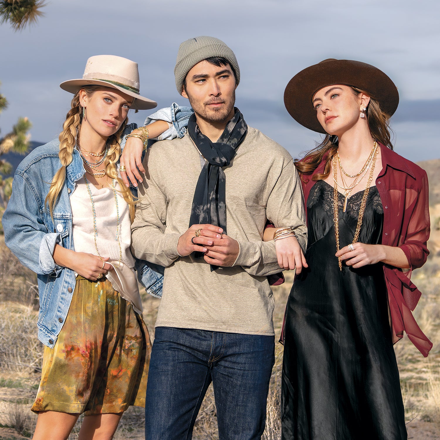 Three friends standing in desert wearing 18k golds, diamond, turquoise, pink diamond jewelry + designer hats and silk apparel, all by Dominique Cohen; phone 323-404-2959 for shopping help.