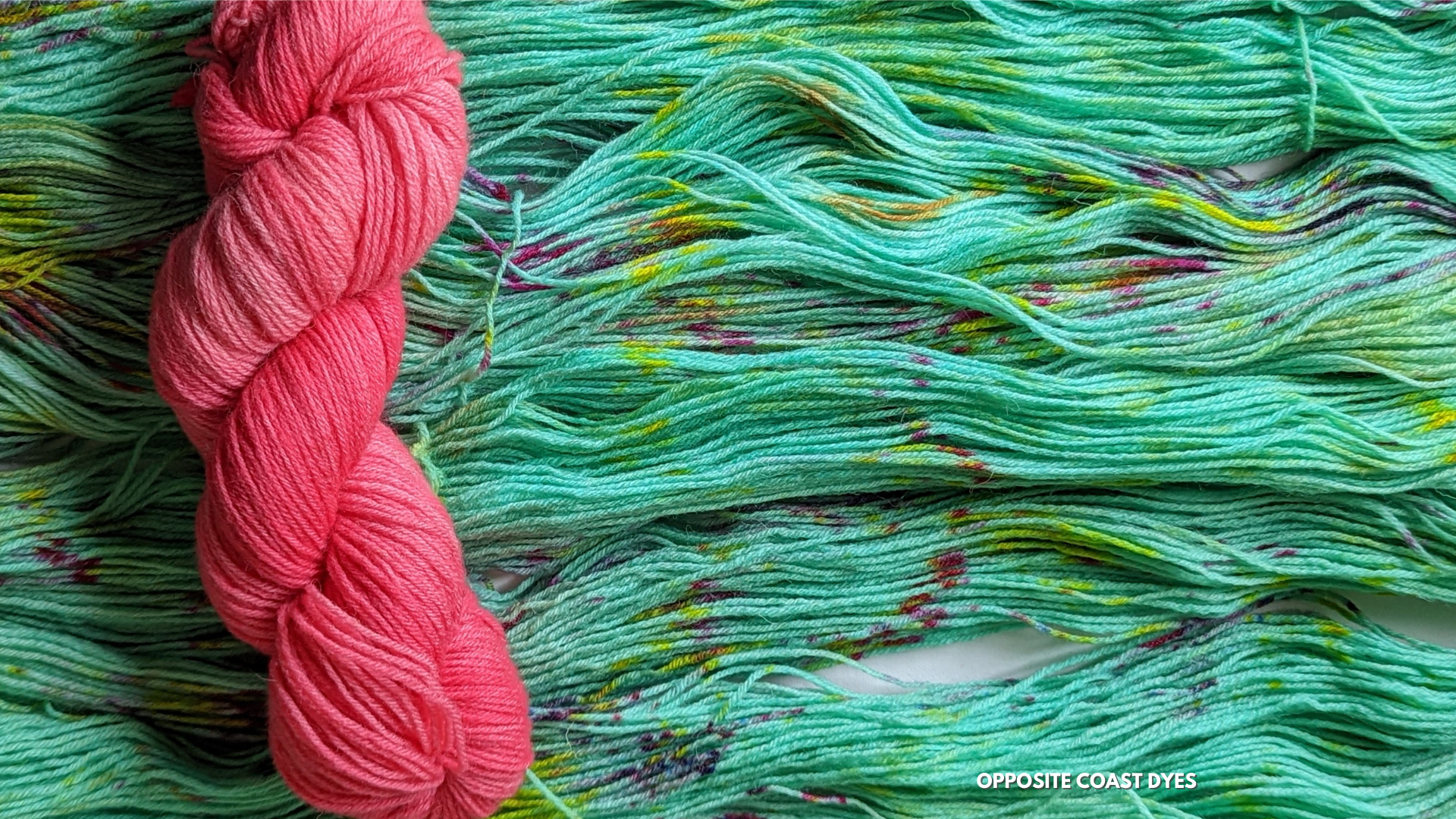 unwound green yarn with pink and yellow speckles, bright pink wound yarn to the left on top of green yarn