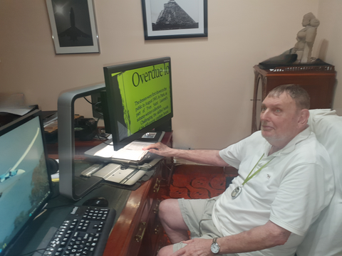 Peter sitting at his desk in front of ClearView desktop magnifier and computer